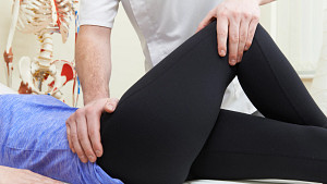 Practitioner administering an examination of a woman patient&#039;s hip.