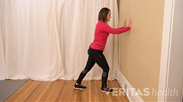 Woman doing a Standing Calf Muscle Stretch against a wall.