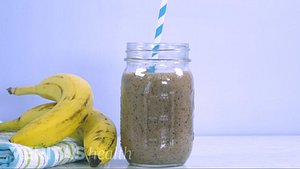 Bananas on a table top next to a blueberry mango smoothie in a mason jar.