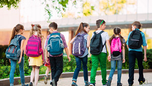 Vista de siete niños caminando con mochilas en la escuela.