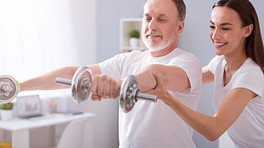 physical therapist leading man through a series of arm exercises with weights