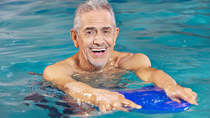 Man in a pool performing water aerobics.