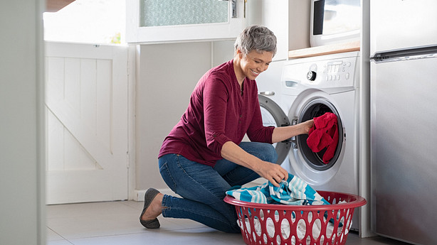 Woman squatting to get laundry out of the dryer.