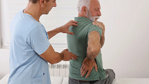 Doctor evaluating patient&#039;s spine and shoulder.