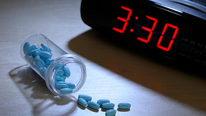 Digital clock reading 3:30 with sleeping pills scattered on the table.
