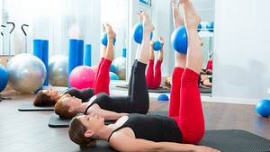 women lying on exercise mat with Pilates ball