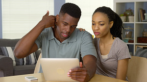 Young man holding his neck and reading a tablet with his girlfriend