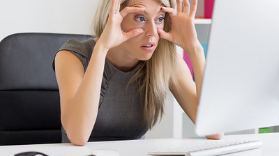 Woman forcing her eyes open to look at her computer.