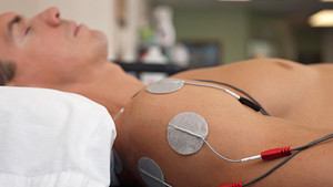 Tens unit attached to a young man&#039;s shoulder