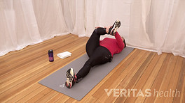 Woman doing a supine piriformis stretch.