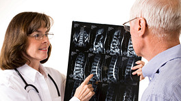 Doctor and patient having a discussion in an office while looking at scans.