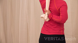 Posterior view of woman doing towel shoulder stretch