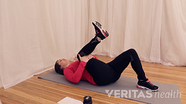 Woman lying supine doing Single Knee to Chest SI Joint Stretch
