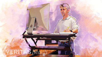 Man using a standing desk converter in his office