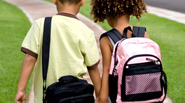 Children walking to school carrying a backpack and messenger bag