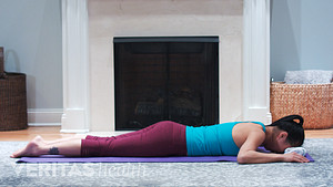 Woman laying prone on a mat performing the prone cobra neck strengthening exercise