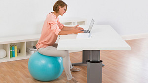 Woman sitting on an exercise ball at her desk.