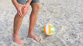 人抓住膝盖旁边在沙滩排球