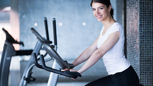 Woman riding stationary bicycles at the gym.