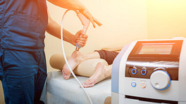 Physician using shock wave therapy on a patients heel for plantar fasciitis