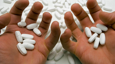 Pair of hands hold several prescription pills