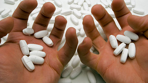Pair of hands hold several prescription pills