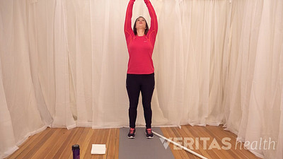 Woman stretching both arms above her head while looking up towards her hands