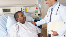 Doctor speaking with a patient in a hospital bed.