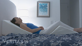 Woman sleeping with a wedge pillow underneath her back and legs.
