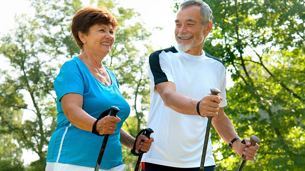 An older couple using walking sticks on their hike
