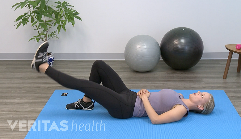 Woman performing straight leg raises on a yoga mat.