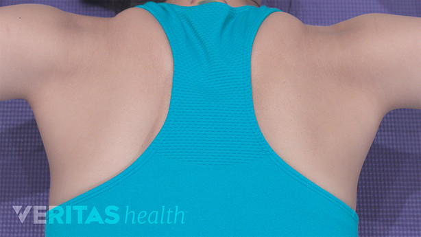 Back and shoulders of a woman doing a prone cobra stretch.